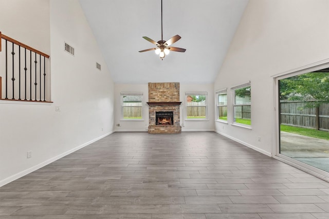 unfurnished living room featuring high vaulted ceiling, a ceiling fan, wood finished floors, a large fireplace, and baseboards