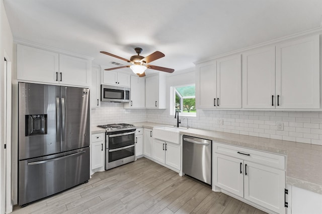 kitchen with stainless steel appliances, a ceiling fan, a sink, and white cabinetry