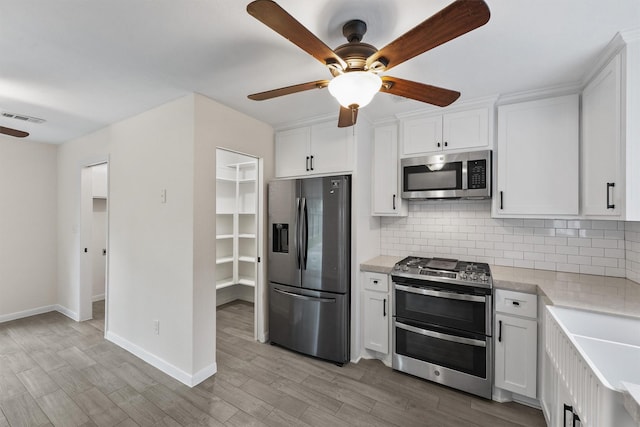 kitchen with stainless steel appliances, ceiling fan, light countertops, tasteful backsplash, and white cabinets