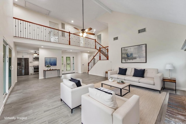 living room featuring ceiling fan, high vaulted ceiling, light wood-style floors, beam ceiling, and baseboards