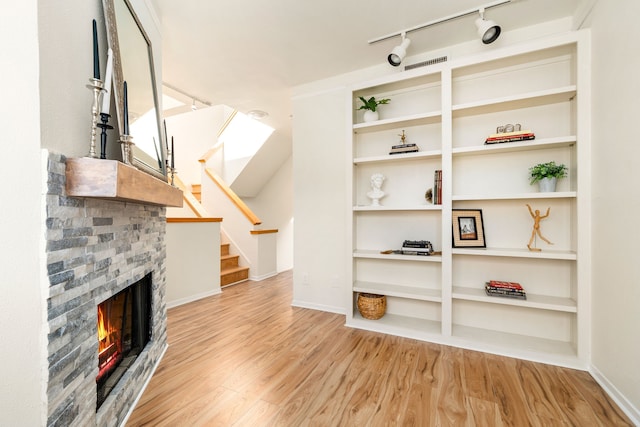 2100 Huldy St Unit 4, Houston, TX 77019 - unfurnished living room featuring wood finished floors, a brick fireplace, stairway, rail lighting, and baseboards