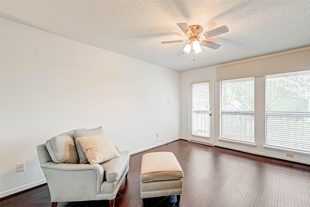 living area featuring ceiling fan, a textured ceiling, baseboards, and dark wood-style floors