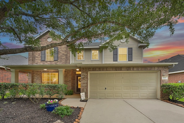 traditional-style home with concrete driveway, an attached garage, brick siding, and covered porch
