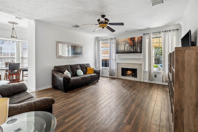 2112 Shadow Bay Cir, League City, TX 77573 - living room featuring dark wood-style floors, a ceiling fan, a tile fireplace, a textured ceiling, and baseboards