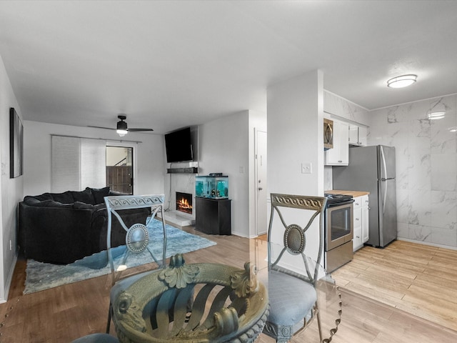 dining area featuring a premium fireplace, a ceiling fan, and light wood-style flooring