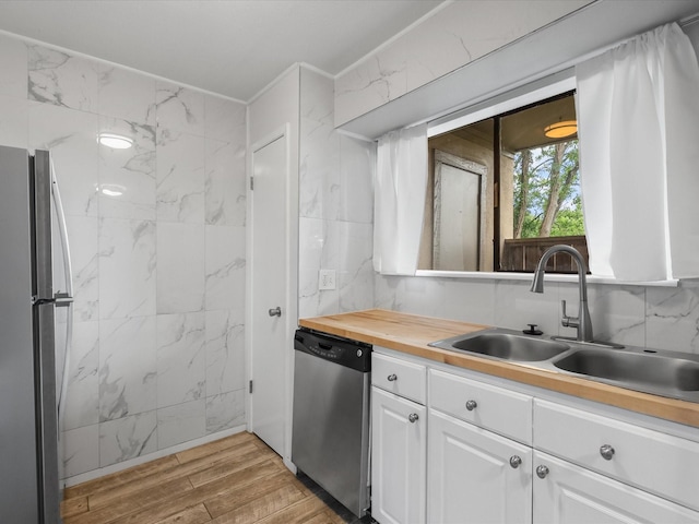 kitchen featuring appliances with stainless steel finishes, a sink, white cabinetry, and light wood finished floors