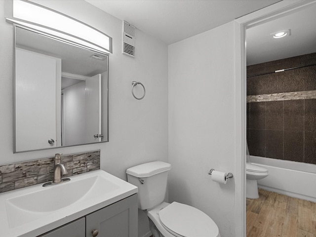 full bathroom featuring toilet, vanity, wood finished floors, backsplash, and tub / shower combination