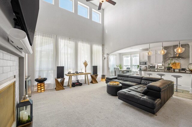 2723 Camellia Ave, Brookshire, TX 77423 - living room featuring a ceiling fan, arched walkways, a towering ceiling, and a brick fireplace