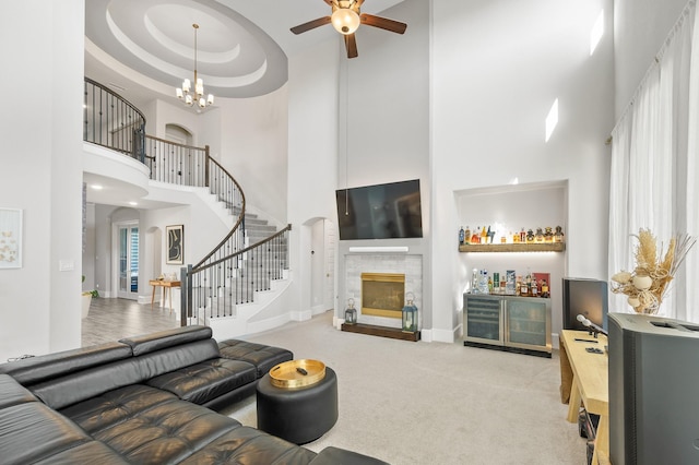 2723 Camellia Ave, Brookshire, TX 77423 - living room featuring a towering ceiling, ceiling fan, a glass covered fireplace, stairway, and carpet