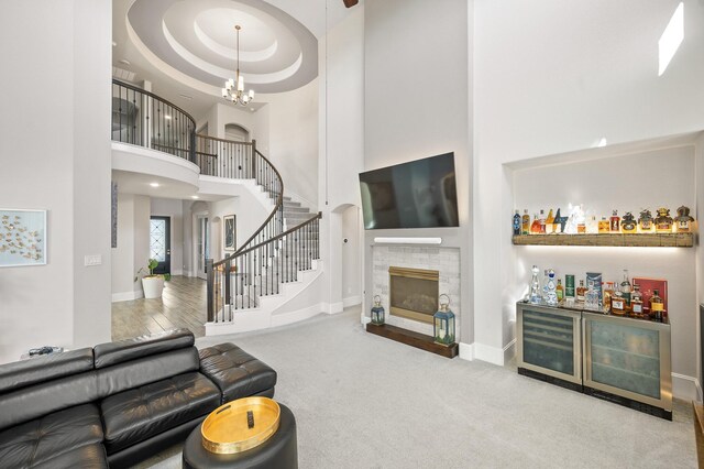 2723 Camellia Ave, Brookshire, TX 77423 - carpeted living area featuring a high ceiling, a glass covered fireplace, stairs, a dry bar, and baseboards