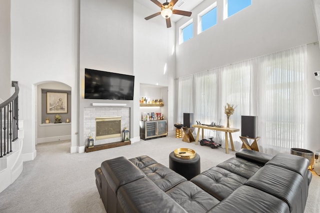 2723 Camellia Ave, Brookshire, TX 77423 - carpeted living room featuring a towering ceiling, a ceiling fan, a brick fireplace, baseboards, and stairway
