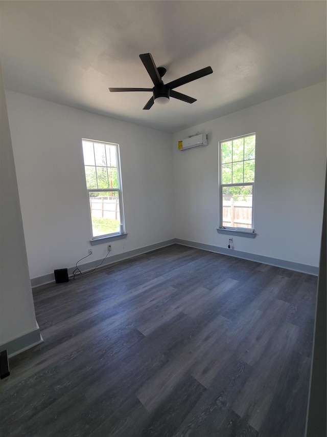 unfurnished room with a wall mounted air conditioner, ceiling fan, dark wood-type flooring, and baseboards