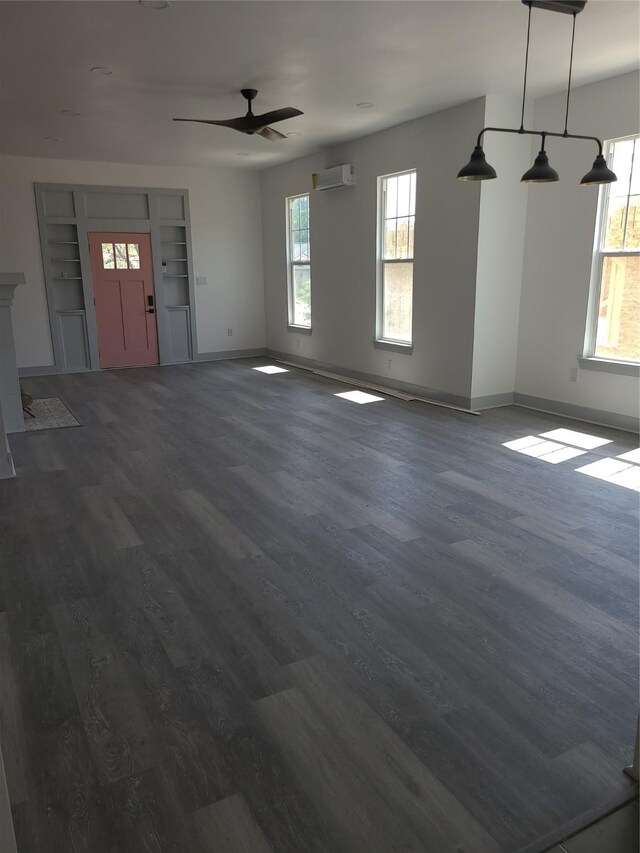 unfurnished living room featuring an AC wall unit, dark wood-style floors, a ceiling fan, and healthy amount of natural light