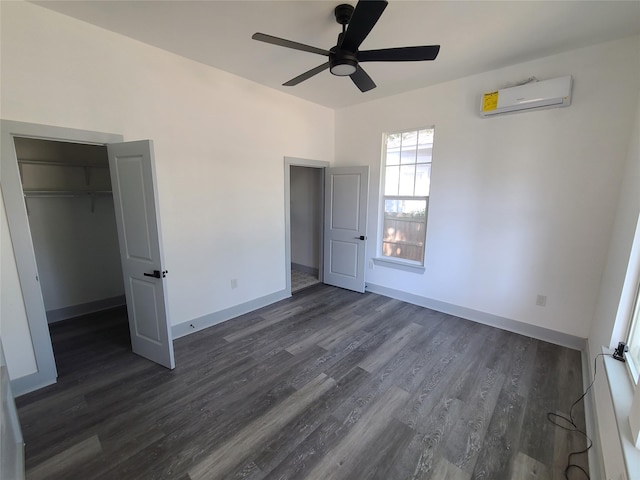 unfurnished bedroom featuring a wall mounted AC, dark wood-style flooring, baseboards, and a ceiling fan