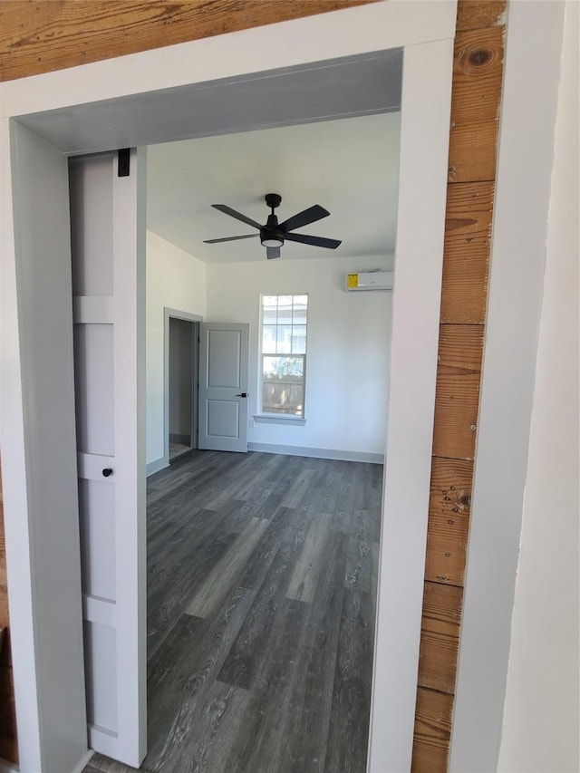 empty room featuring dark wood-type flooring, a ceiling fan, and baseboards