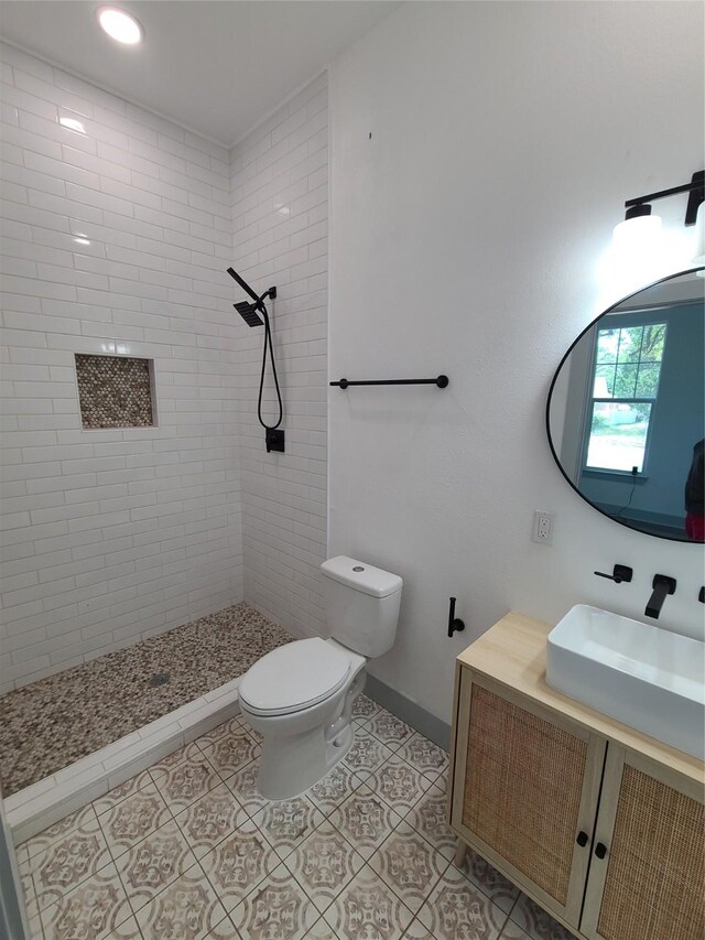 full bathroom featuring a tile shower, toilet, tile patterned floors, and vanity