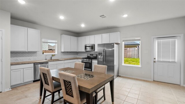 22218 Delphin Grove Dr, Hockley, TX 77447 - kitchen with stainless steel appliances, backsplash, white cabinets, recessed lighting, and light tile patterned flooring
