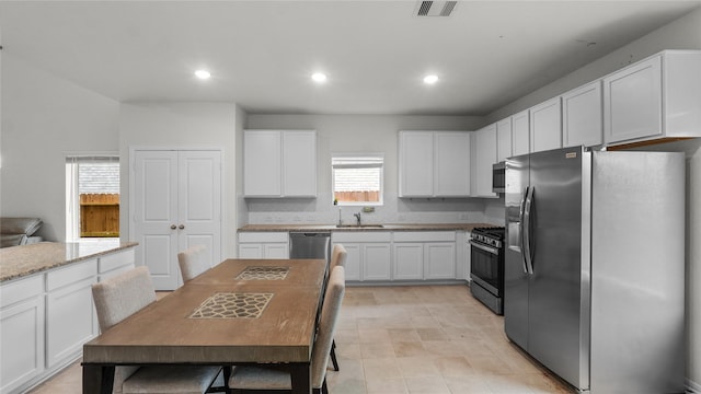 22218 Delphin Grove Dr, Hockley, TX 77447 - kitchen with stainless steel appliances, a sink, white cabinetry, recessed lighting, and light stone counters
