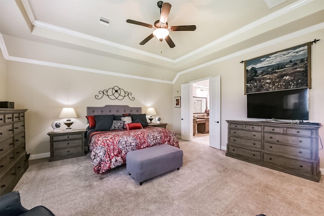 carpeted bedroom featuring a tray ceiling, ornamental molding, baseboards, ensuite bath, and a ceiling fan