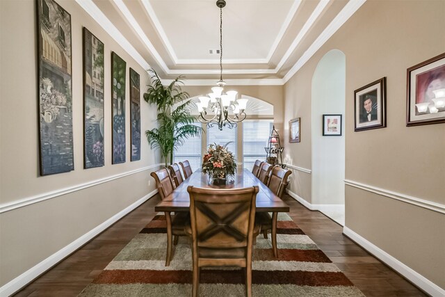 dining area featuring a tray ceiling, dark wood-type flooring, a chandelier, arched walkways, and crown molding