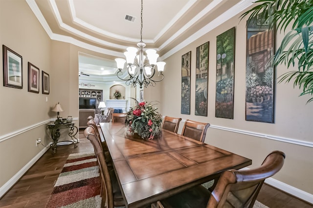 dining area featuring a tray ceiling, a chandelier, crown molding, dark wood-style floors, and baseboards