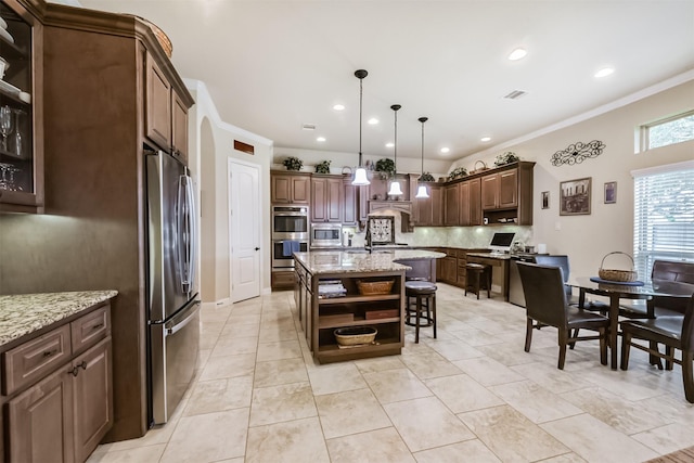 kitchen with appliances with stainless steel finishes, backsplash, open shelves, an island with sink, and a kitchen breakfast bar