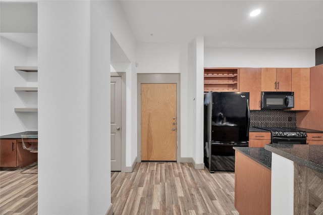 kitchen featuring black appliances, open shelves, light wood-style flooring, dark stone counters, and decorative backsplash
