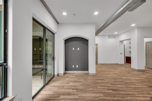 spare room featuring light wood-style floors, baseboards, recessed lighting, arched walkways, and a smoke detector
