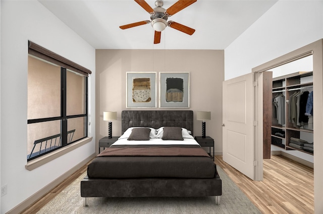 bedroom with light wood finished floors, a closet, a spacious closet, and a ceiling fan