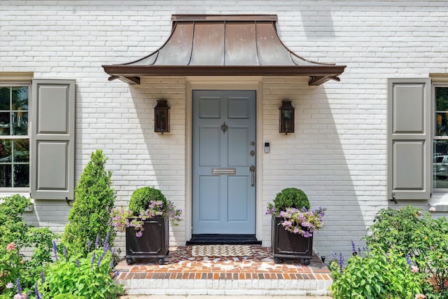 property entrance with brick siding and a standing seam roof