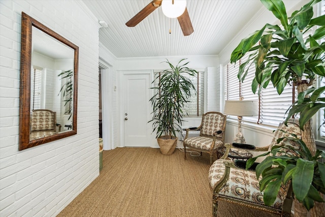 sitting room featuring ceiling fan, carpet floors, brick wall, healthy amount of natural light, and ornamental molding