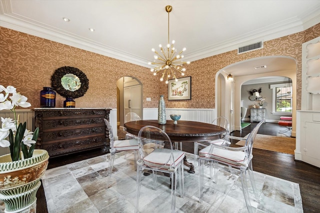 dining area featuring arched walkways, ornamental molding, a wainscoted wall, wallpapered walls, and a chandelier