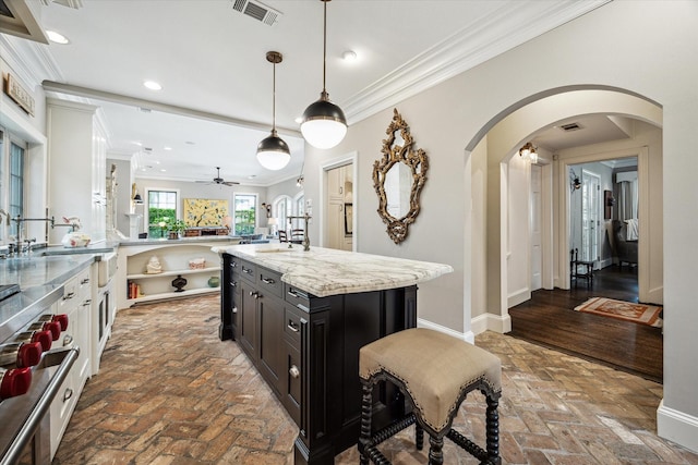 kitchen featuring ornamental molding, ceiling fan, arched walkways, brick flooring, and recessed lighting