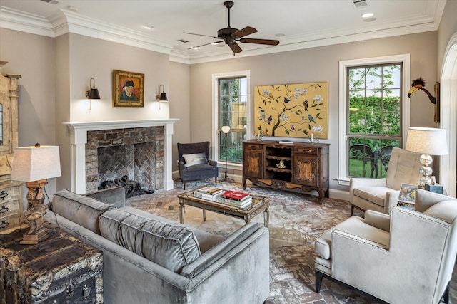 living room with a brick fireplace, plenty of natural light, ceiling fan, ornamental molding, and brick floors