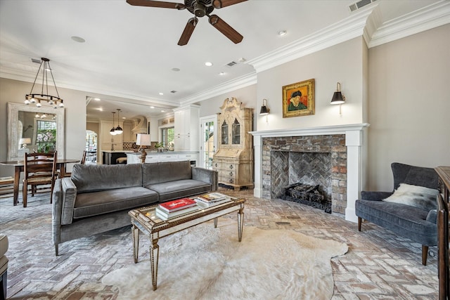 living room with a brick fireplace, brick floors, a ceiling fan, ornamental molding, and plenty of natural light