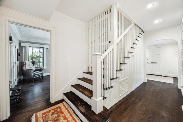 stairway with arched walkways, wood finished floors, baseboards, and recessed lighting