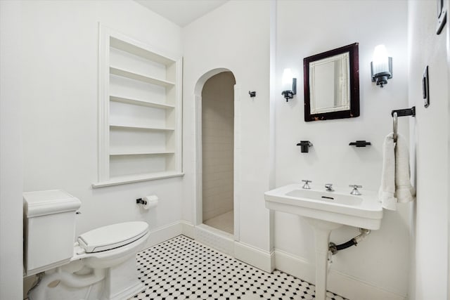 bathroom with toilet, a shower stall, and baseboards