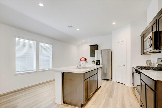 12319 Tranquil Pines Dr, Houston, TX 77014 - kitchen featuring appliances with stainless steel finishes, a sink, light wood-style flooring, light countertops, and an island with sink
