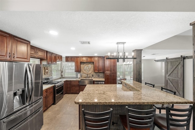 996 Scroggins Ln, Waller, TX 77484 - kitchen with stainless steel appliances, a barn door, tasteful backsplash, a large island, and a kitchen bar