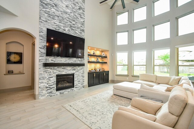 living area with a high ceiling, ceiling fan, healthy amount of natural light, and a fireplace