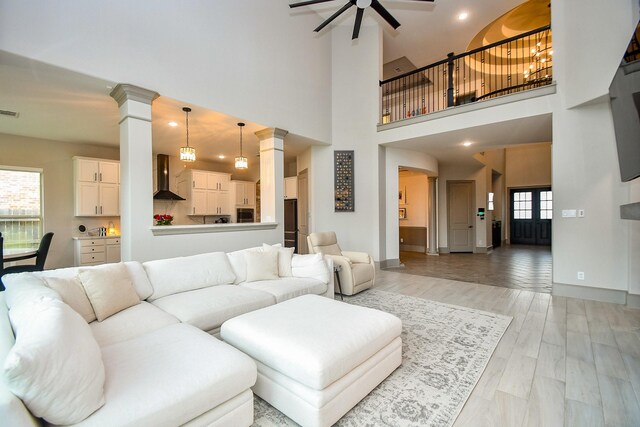 living area featuring decorative columns, a ceiling fan, baseboards, a high ceiling, and recessed lighting
