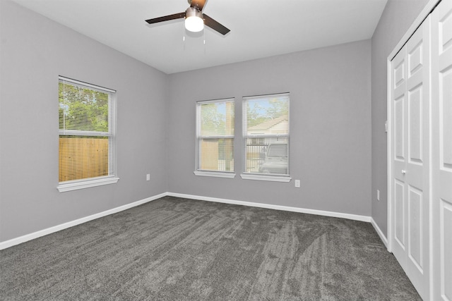 unfurnished bedroom with a closet, multiple windows, and dark carpet