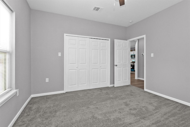 unfurnished bedroom with multiple windows, carpet, a closet, and a ceiling fan