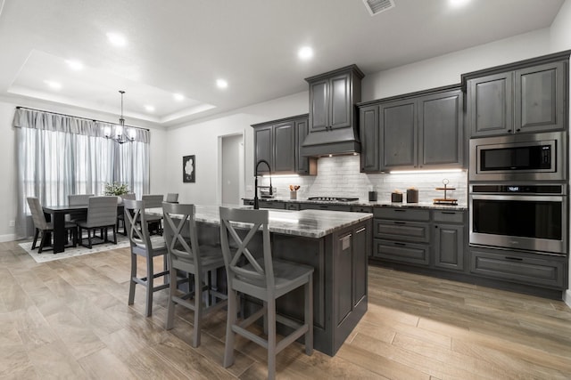 100 Calvary Dr, Adkins, TX 78101 - kitchen with appliances with stainless steel finishes, a chandelier, light stone counters, an island with sink, and tasteful backsplash