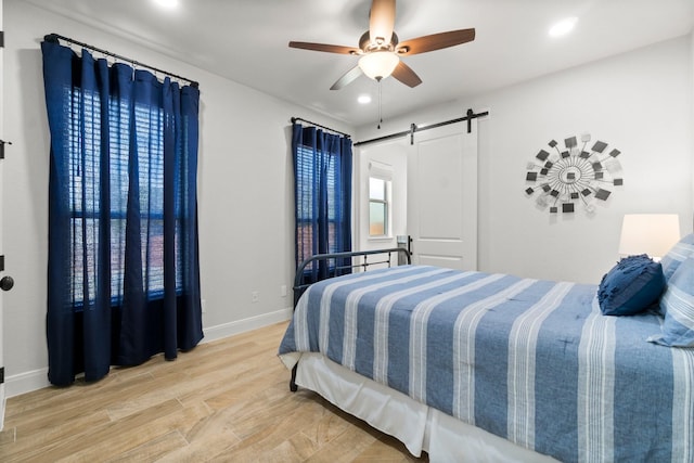 100 Calvary Dr, Adkins, TX 78101 - bedroom featuring a barn door, baseboards, wood finished floors, recessed lighting, and ceiling fan