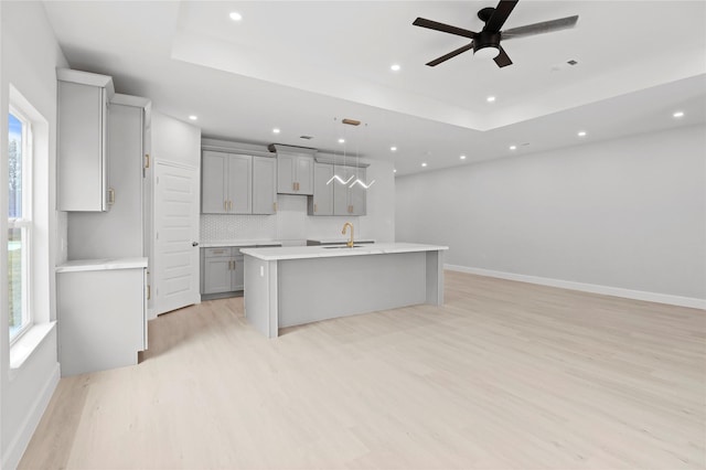 kitchen featuring gray cabinetry, recessed lighting, light wood-style floors, a kitchen island with sink, and plenty of natural light