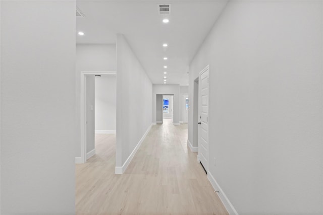 hallway featuring light wood finished floors, recessed lighting, and baseboards