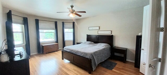 bedroom with light wood-type flooring, baseboards, and a ceiling fan