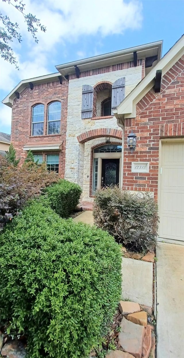 view of exterior entry with a garage and brick siding