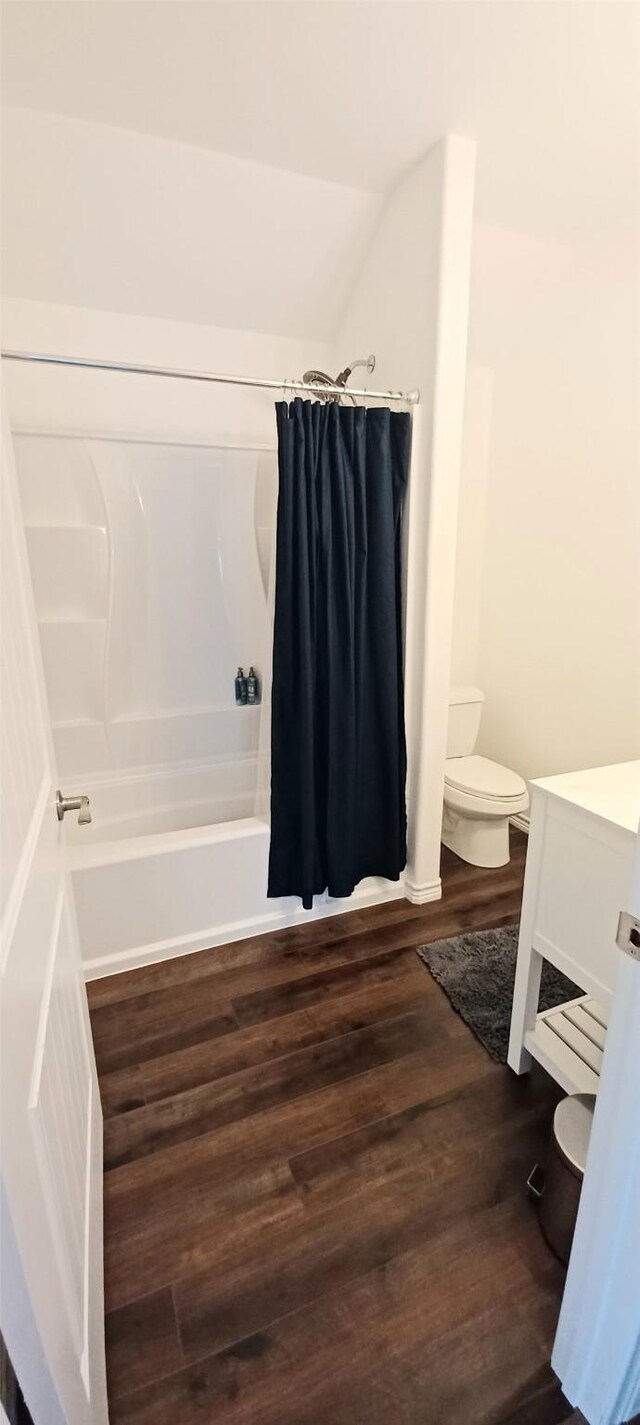bathroom with toilet, wood finished floors, shower / bath combo, and vanity